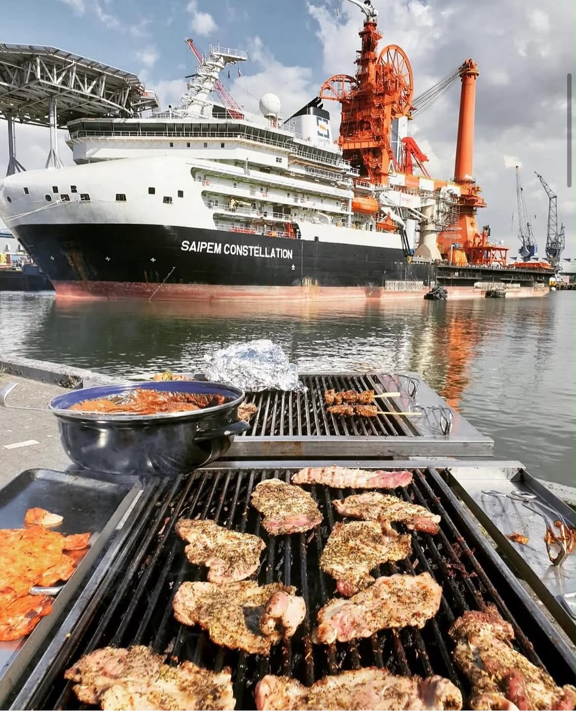 Volle grill aan de kade met een zeeschip op de achtergrond