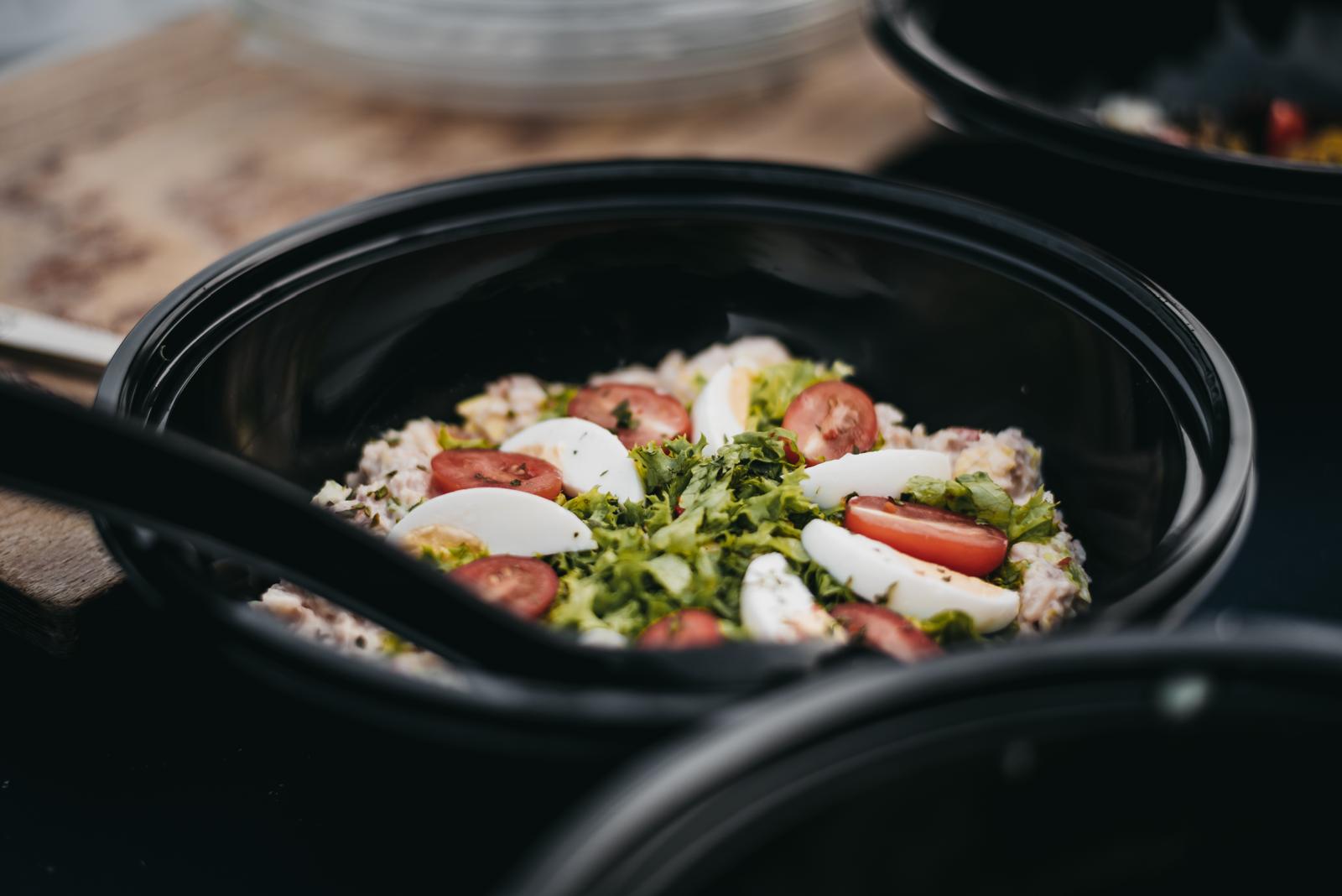 Verse salade met tomaat en ei in een zwarte serveerschaal
